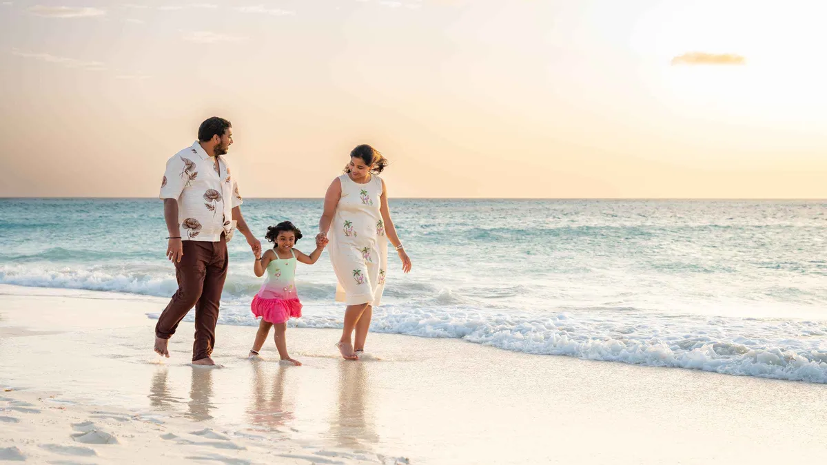 A family of four posing barefoot on Eagle Beach at golden hour during an Aruba photoshoot, Aruba